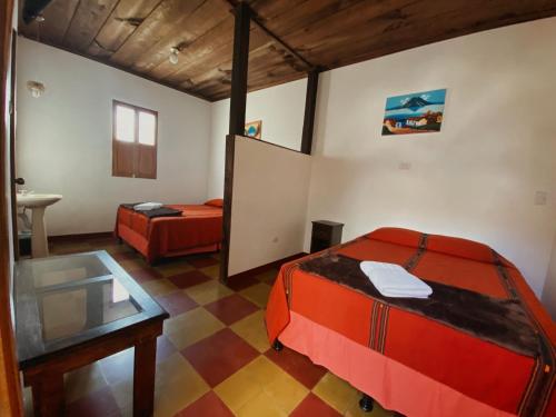 a room with two beds and a table and a mirror at Anexo By Hotel Maya Ik' in Antigua Guatemala