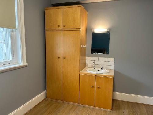 a bathroom with a sink and a wooden cabinet at Bigg Market Apartments in Newcastle upon Tyne