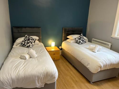 a bedroom with two beds and a table with a lamp at Bigg Market Apartments in Newcastle upon Tyne