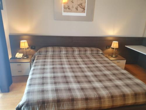 a bedroom with a bed with a plaid blanket on it at eq hotel in Travagliato