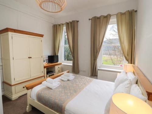 a bedroom with a bed and a cabinet and two windows at The Dower House in Keswick