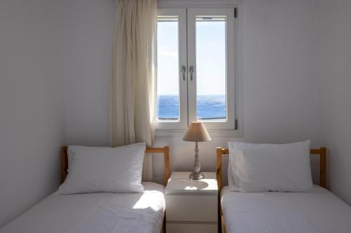 twee bedden in een kamer met twee ramen bij White Holidays Project Ag. Sostis in Agios Sostis
