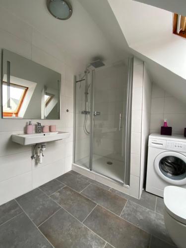 a bathroom with a shower and a washing machine at Altes Zollhaus in Borkum