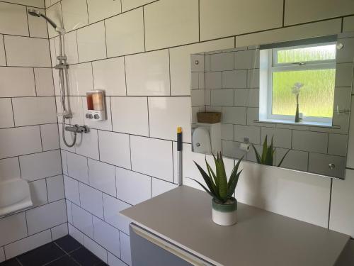 a white tiled bathroom with a sink and a window at Number 3, Lytton Tree Lodge, Reydon, Southwold in Reydon