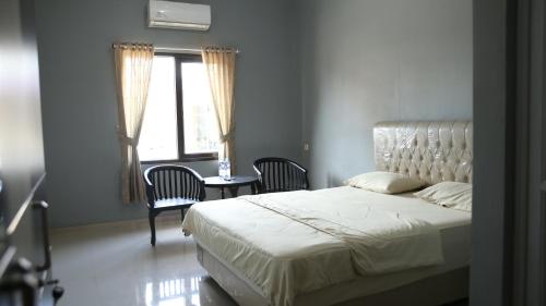 um quarto com uma cama, uma mesa e cadeiras em Cemara Guest House Syariah Kertajati 