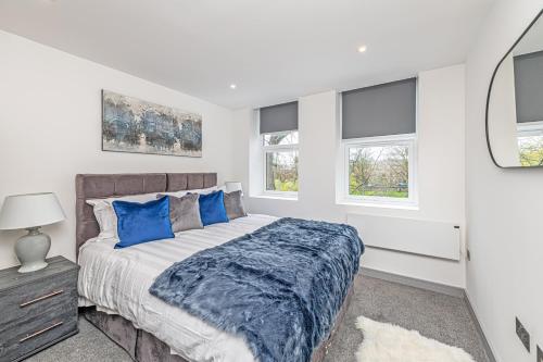 ein Schlafzimmer mit einem Bett und zwei Fenstern in der Unterkunft Charles House Serviced Apartments in Preston