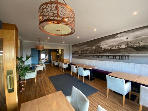 a restaurant with wooden tables and chairs and a mural at The Calder House Hotel in Seascale