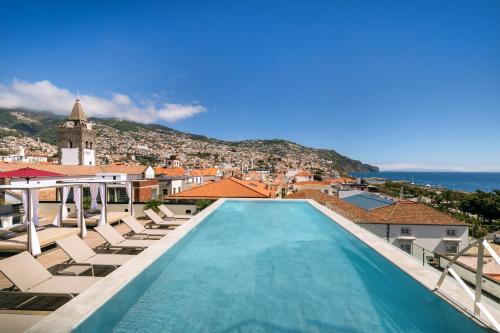 a view of a pool with chairs and a city at Barceló Funchal Oldtown in Funchal