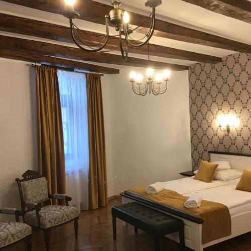 a bedroom with a bed and a chair and a chandelier at Casa Wagner in Sibiu