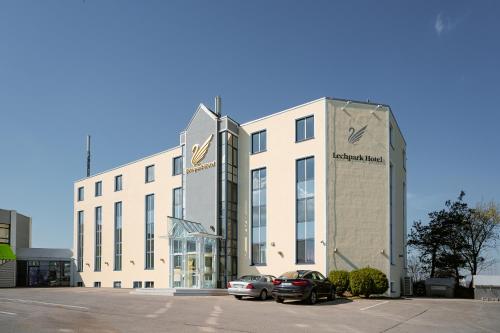a building with two cars parked in a parking lot at Lechpark Hotel in Untermeitingen