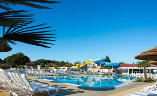 a large swimming pool with chairs and umbrellas at - Mobilhome Camping Les Charmettes - Fun pass non inclus - in Les Mathes
