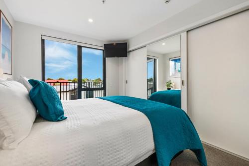 a bedroom with a large bed with blue pillows at Barbadoes Beauty - Christchurch Holiday Apartment in Christchurch