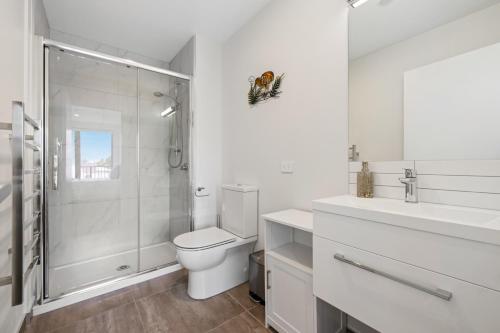 a white bathroom with a toilet and a shower at Barbadoes Beauty - Christchurch Holiday Apartment in Christchurch