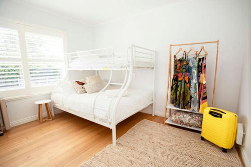 a bedroom with a white bunk bed and a yellow suitcase at Beachside Getaway Bay Views North Shore VIC Sleeps 12 Free Wifi in North Shore