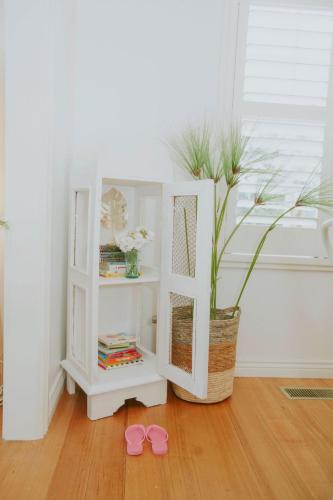 a white shelf with a potted plant and a pair of pink shoes at Beachside Getaway Bay Views North Shore VIC Sleeps 12 Free Wifi in North Shore