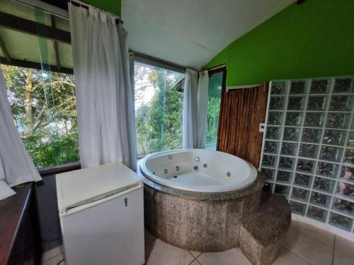 uma casa de banho com uma grande banheira em frente a uma janela em Chalés Pico do Caledônia em Nova Friburgo