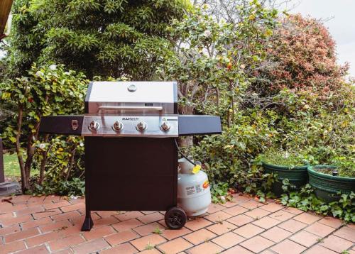 a grill sitting on a brick patio with a compressor at Very Cool Mid Century, Pet Friendly Urban Oasis in Geelong