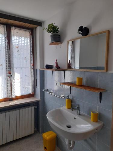 uma casa de banho com um lavatório e um espelho em La Mëisun em Perrero