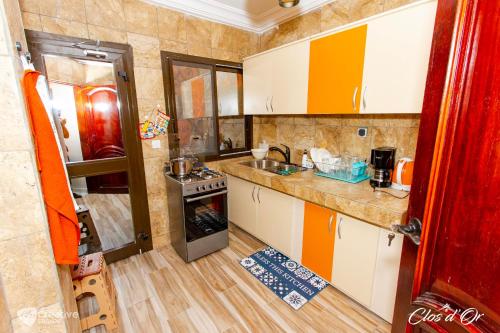 una pequeña cocina con armarios naranjas y blancos en Clos d'Or, Appartements meublés Douala Makepé, en Douala