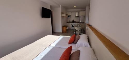 1 dormitorio con 1 cama grande con almohadas de color naranja en Estudios en Plaza Cabo da Vila centro Muxia, en Muxía