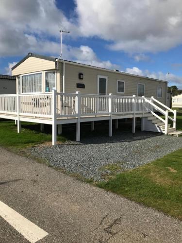 a house with a white porch and a white fence at Lizard ,Mullion holiday caravan in Mullion