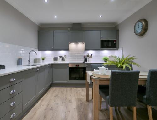 une cuisine avec des placards gris et une table en bois dans l'établissement Durham Riverside Apartments, à Durham