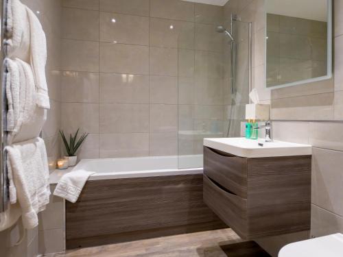 a bathroom with a bath tub and a sink at Durham Riverside Apartments in Durham