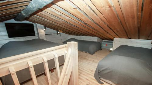 two beds in a room with a wooden ceiling at Ski-in-out FreeRider in Pyhätunturi