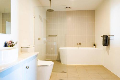 uma casa de banho com uma banheira, um WC e um lavatório. em Luxury Beach Front Apartment Moana - Waterviews em Moana