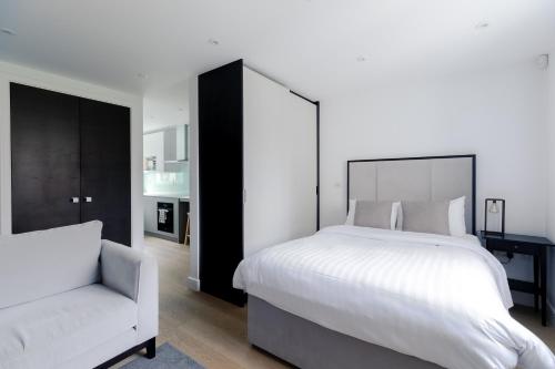 a bedroom with a large white bed and a chair at StayInn Aldgate in London