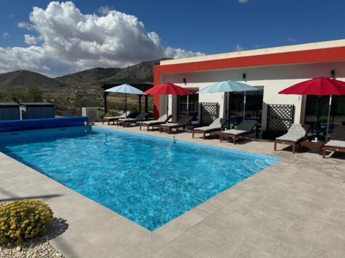 a swimming pool with chairs and umbrellas next to a building at Casa Andmar - Mountain retreat in La Romana