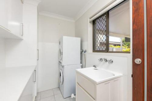 a white kitchen with a sink and a refrigerator at Mooloolaba Escape to Mooloolaba & Feel At Home in Style in Mooloolaba