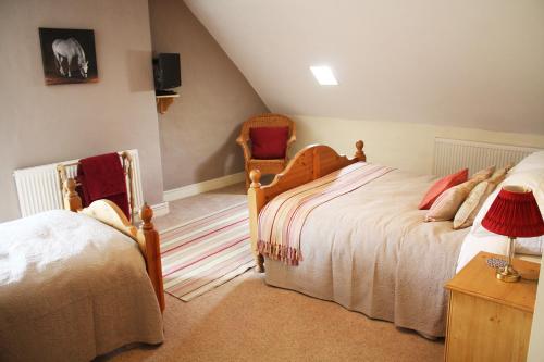 a bedroom with two beds and a chair at Willow Tree Farm in Hillington