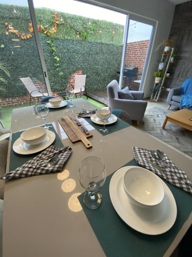 a table with plates and wine glasses on it at Casa familiar cerca de la playa con terraza privada in Cancún