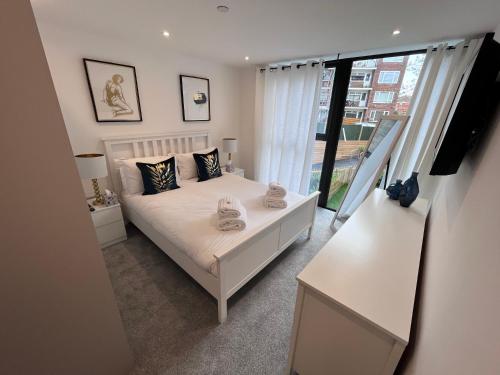 una camera con un letto bianco e una grande finestra di Aurora Ashley Cross a Poole