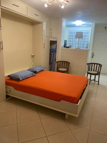 a large bed in a room with two chairs at Madinigwa au Trois-Ilets in Fort-de-France