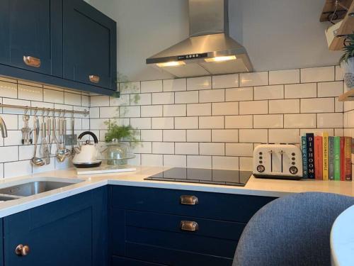 uma cozinha com armários azuis, um lavatório e um fogão em Modern Cottage: Free Parking, Garden, Sea Views em St. Agnes