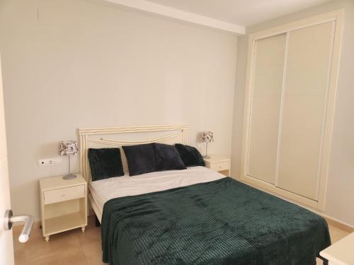 een slaapkamer met een bed met een groene deken bij Esmeralda Suites in Calpe