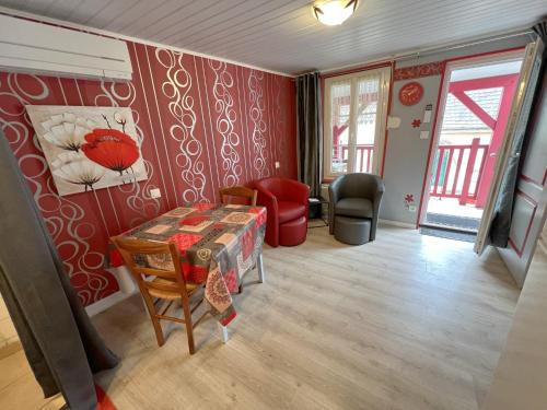 een woonkamer met rode muren en een tafel bij Les Meublés du Rocher - Près du parc LE PAL in Bourbon-Lancy