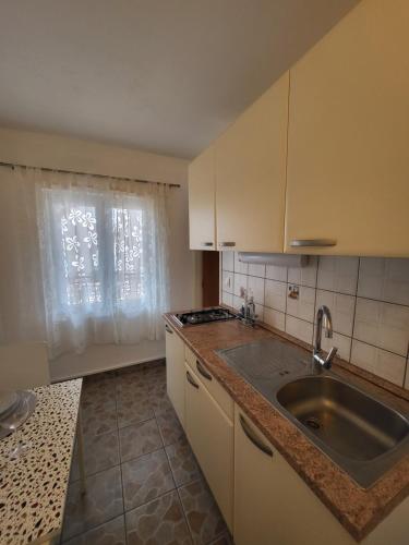 Una pequeña cocina con fregadero y ventana. en ApartmaniinPrimosten, en Primošten