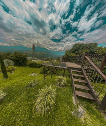 a wooden bridge in a field with a cloudy sky at All Natural Glamping in Copacabana