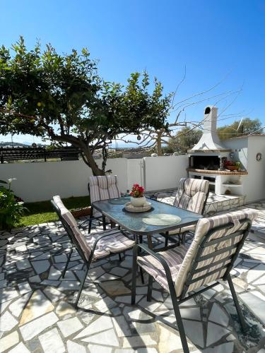 een patio met een tafel en stoelen en een grill bij Sunny Beach House in Korinthos