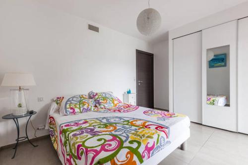 une chambre avec un grand lit avec une couverture colorée dans l'établissement T2 d'exception 100m plage terrasse vue mer et montagnes, à Propriano