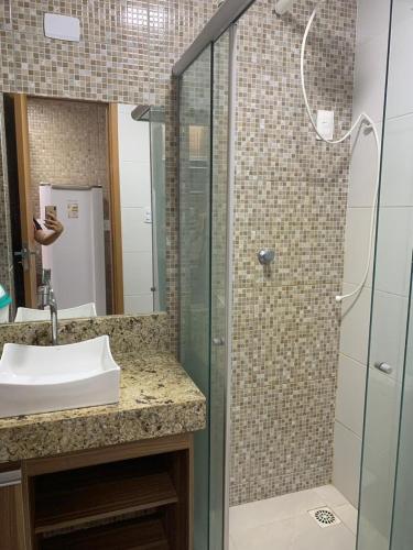 La salle de bains est pourvue d'un lavabo et d'une douche en verre. dans l'établissement Excelente Ap Mobiliado (Ótima Localização) - Com Ar, à Campina Grande