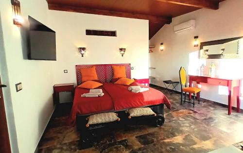 Schlafzimmer mit einem roten Bett und einem Schreibtisch in der Unterkunft Aladin Comfort Country Rooms in Campinho