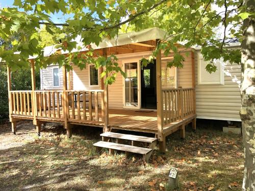 Ce chalet en bois dispose d'une terrasse couverte et de marches. dans l'établissement Mobilhome Confort Moana 1-6 p, Camping Sen-Yan 5 Stars, à Mézos