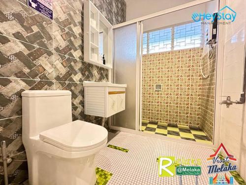 a bathroom with a white toilet and a shower at Klebang Villa 17Pax PrivateSwimmingPool TownArea By Heystay Management in Melaka