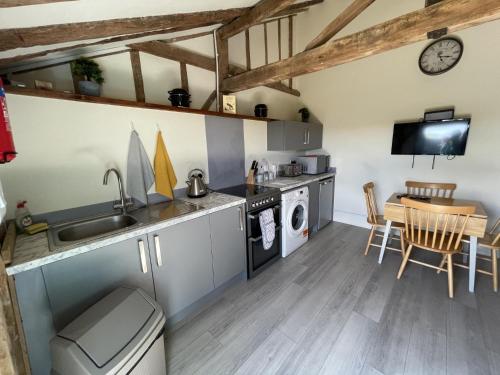 a kitchen and dining room with a sink and a table at The Cow Shed 2-Bed Apartment in Bradwell on Sea in Bradwell on Sea