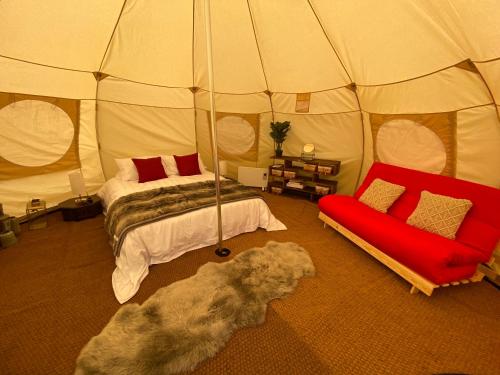 Una habitación con una cama y un sofá en una tienda de campaña en Glamping Red Wharf Bay en Pentraeth