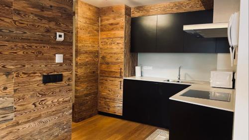 a kitchen with black cabinets and a wooden wall at Appartments Raffele in San Candido